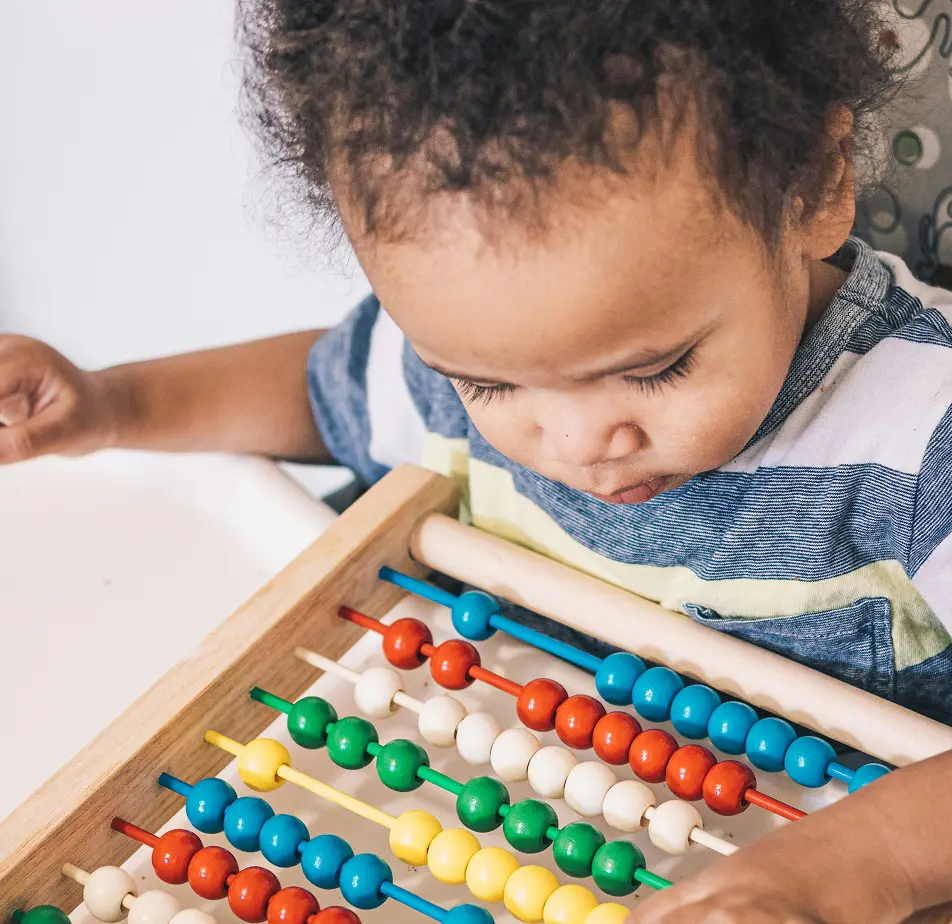 A toddler focused on a wooden abacus — purposeful, engaged play